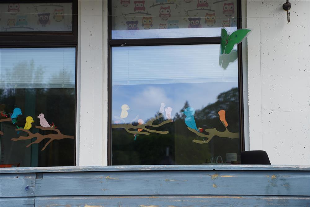 et vindu med utskjæringer av fugler på grener - Klikk for stort bilde