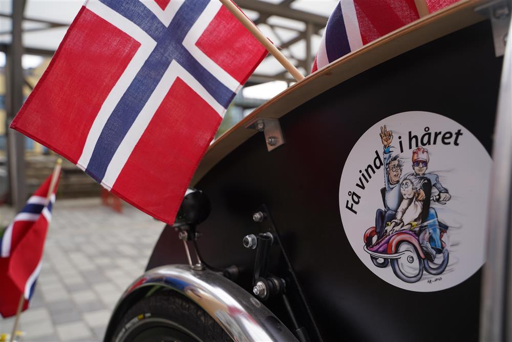 Bilde av forsetet til taxisykkelen, et norsk flagg henger fra setet. Et klistremerke på siden har teksten Få vind i håret - Klikk for stort bilde