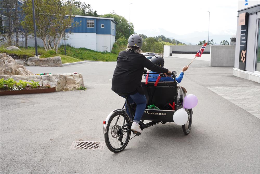 En av beboerene prøver sykkelen mens en av de frivillige sykler - Klikk for stort bilde