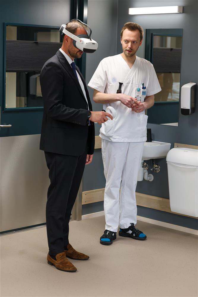 Kronprins Haakon tester ut VR headset med en mann i sykepleieruniform - Klikk for stort bilde